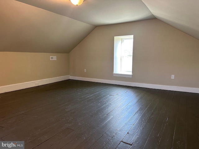 additional living space with dark wood-type flooring and vaulted ceiling