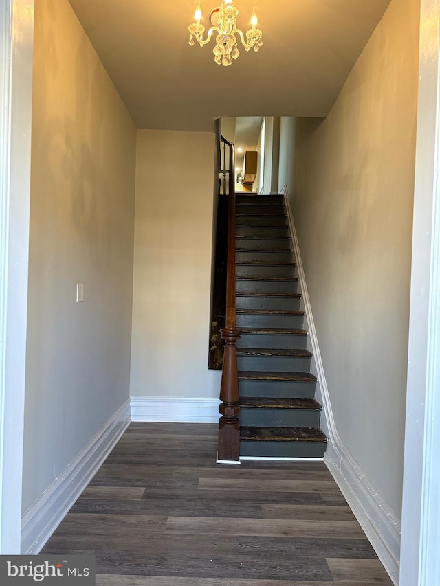 stairs with hardwood / wood-style flooring and a chandelier