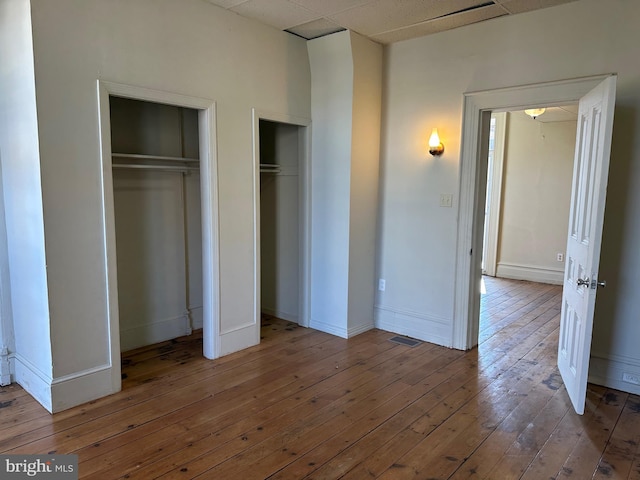 unfurnished bedroom with multiple closets and hardwood / wood-style floors