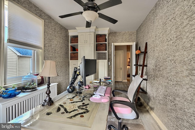 home office with hardwood / wood-style flooring, ceiling fan, and radiator heating unit