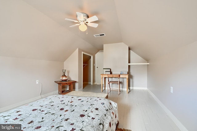 bedroom with ceiling fan, a spacious closet, lofted ceiling, and light wood-type flooring