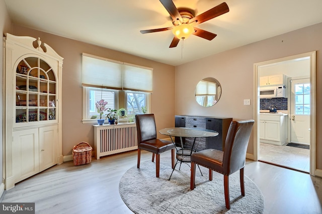 dining area with radiator, ceiling fan, and light hardwood / wood-style flooring