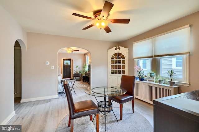 dining space featuring ceiling fan, radiator heating unit, and light hardwood / wood-style floors