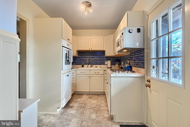 kitchen featuring backsplash, sink, white cabinets, and white appliances