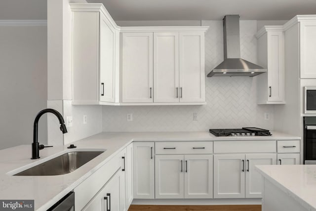 kitchen with wall chimney exhaust hood, sink, appliances with stainless steel finishes, and tasteful backsplash