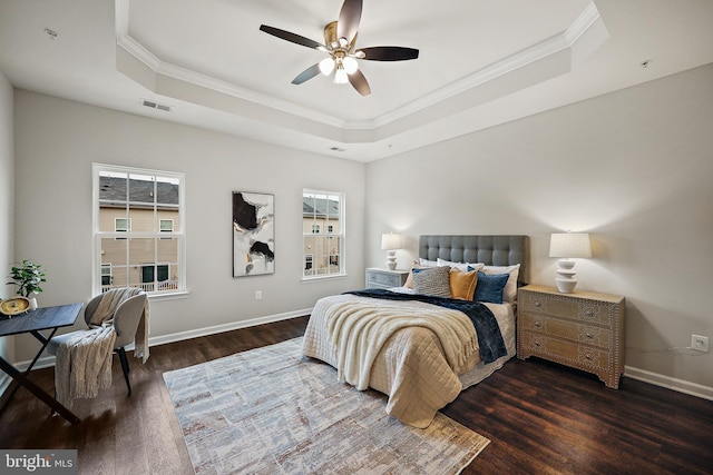 bedroom with ceiling fan, dark hardwood / wood-style floors, ornamental molding, and a tray ceiling