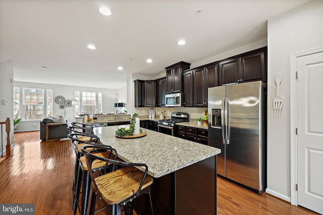 kitchen with a breakfast bar, light wood-type flooring, kitchen peninsula, and appliances with stainless steel finishes