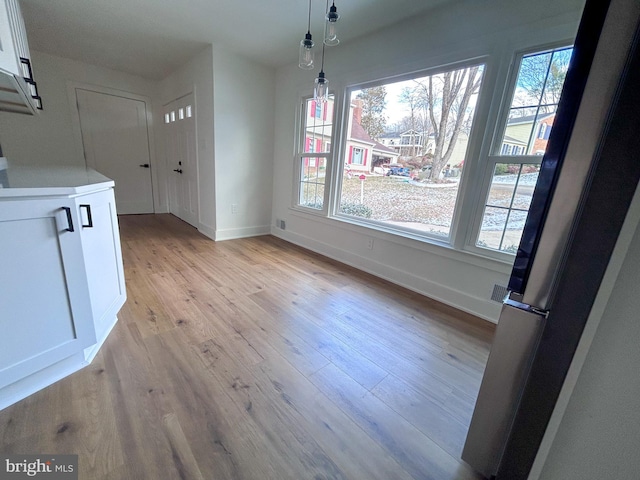 unfurnished dining area featuring light wood-type flooring