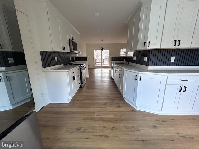 kitchen featuring hardwood / wood-style flooring, white cabinetry, stainless steel range with electric cooktop, and sink