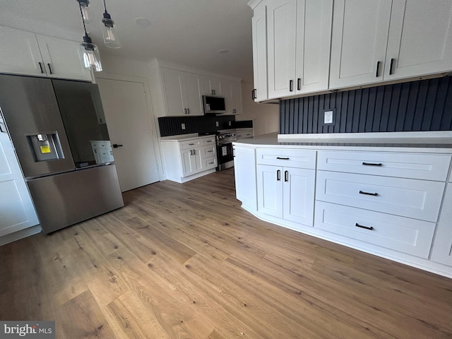 kitchen featuring white cabinets, light hardwood / wood-style floors, decorative light fixtures, and appliances with stainless steel finishes