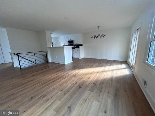 unfurnished living room with hardwood / wood-style floors and a notable chandelier