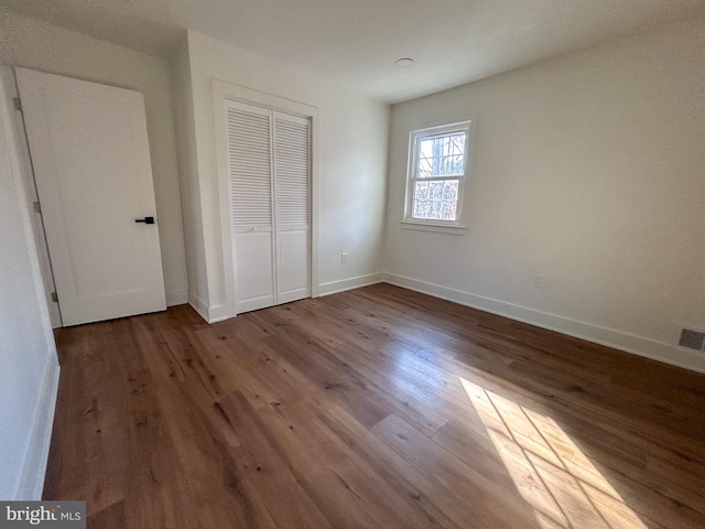 unfurnished bedroom with dark hardwood / wood-style flooring and a closet