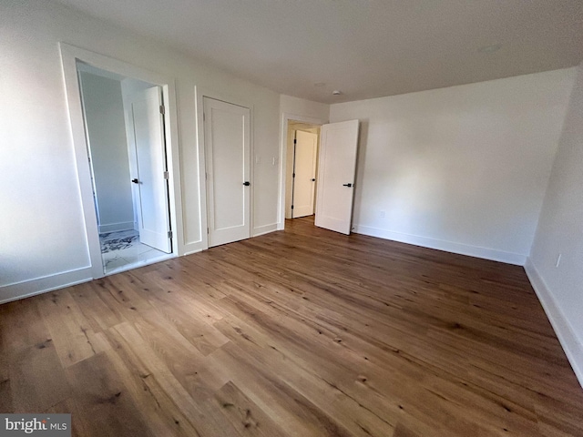 unfurnished bedroom featuring hardwood / wood-style floors and ensuite bathroom