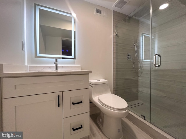 bathroom with vanity, toilet, and a shower with door