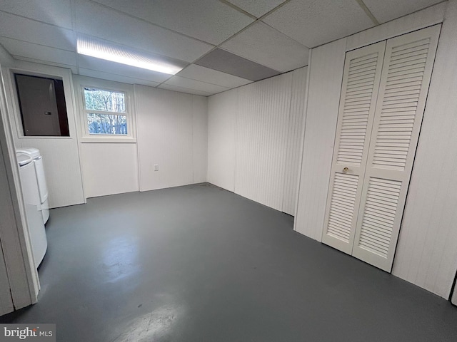 basement featuring washing machine and clothes dryer, a paneled ceiling, and electric panel