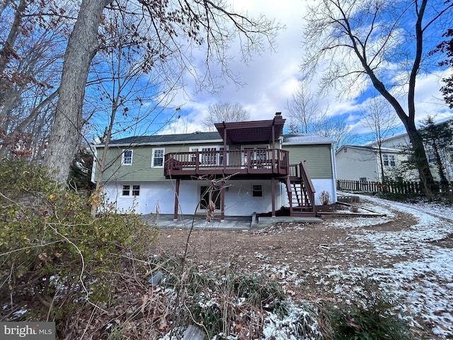 snow covered property featuring a wooden deck and a patio