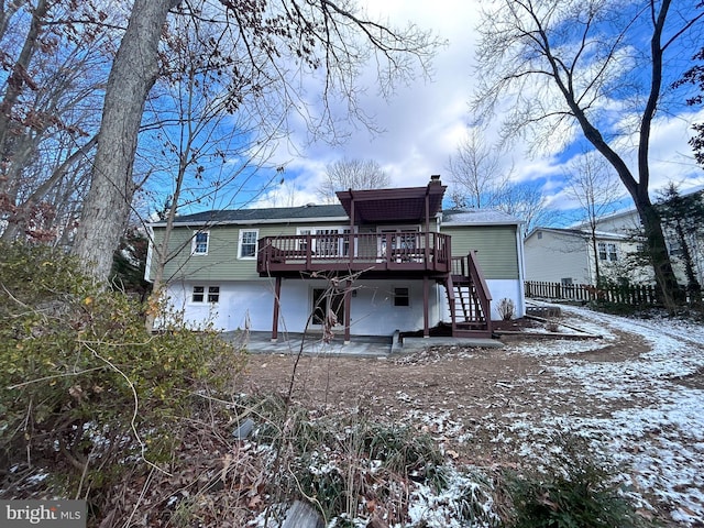 snow covered property with a patio area and a wooden deck