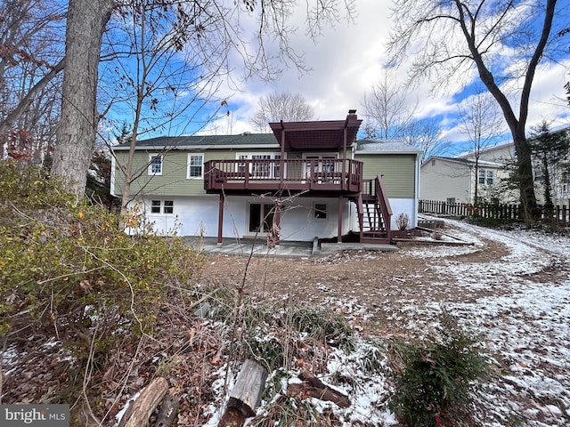 snow covered rear of property featuring a patio and a deck