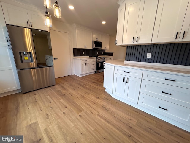 kitchen with white cabinetry, light hardwood / wood-style flooring, pendant lighting, and appliances with stainless steel finishes