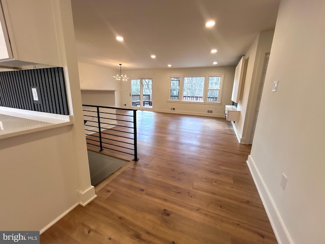 corridor with hardwood / wood-style flooring and an inviting chandelier