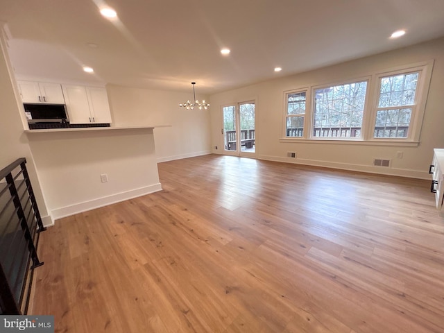 unfurnished living room featuring light hardwood / wood-style floors and a notable chandelier