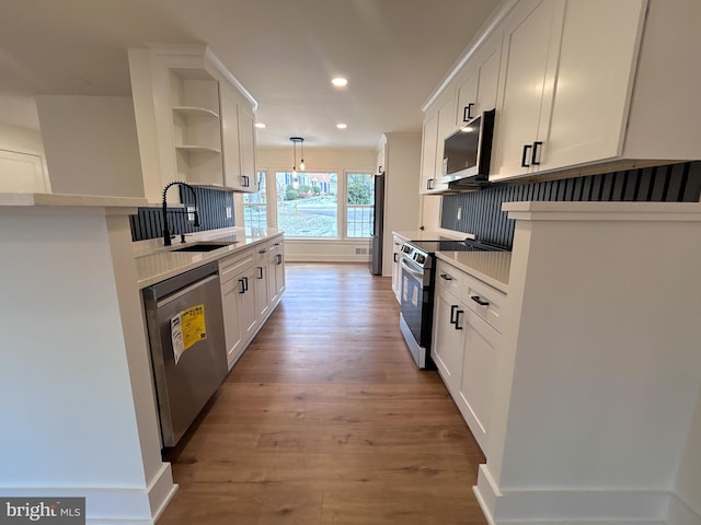 kitchen featuring white cabinets, appliances with stainless steel finishes, hanging light fixtures, and sink