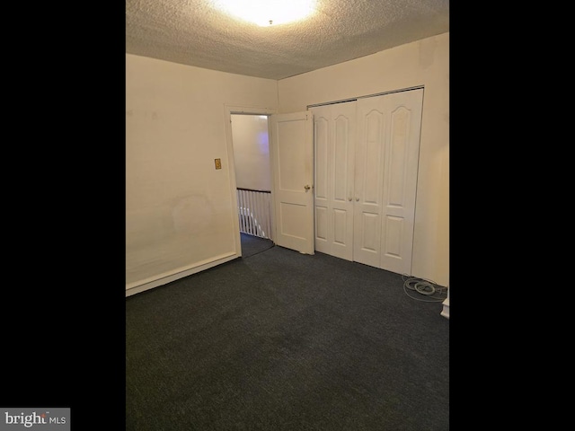 unfurnished bedroom featuring a closet, a textured ceiling, and dark colored carpet