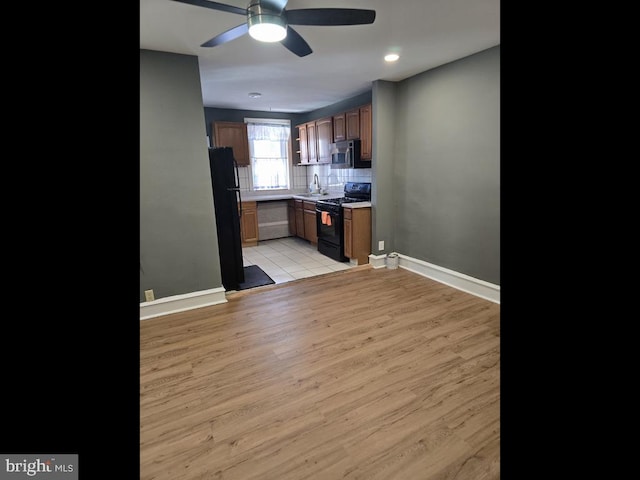 kitchen featuring black appliances, sink, backsplash, ceiling fan, and light hardwood / wood-style floors