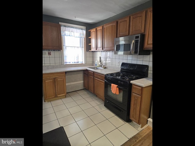 kitchen with tasteful backsplash, sink, gas stove, and light tile patterned floors