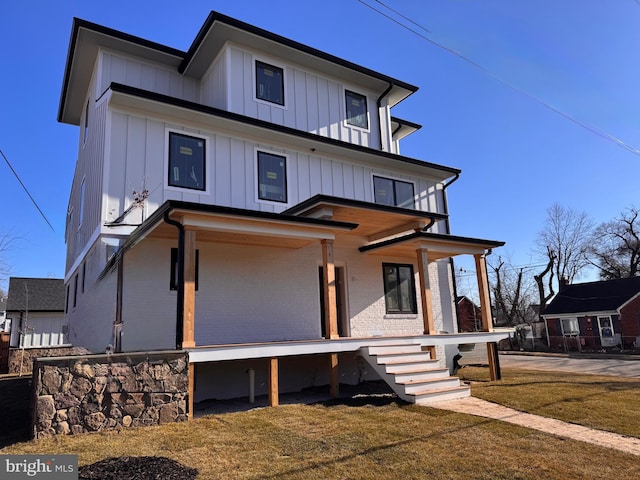 view of front of property featuring board and batten siding, covered porch, and brick siding