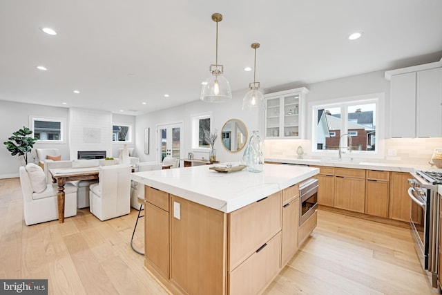 kitchen with stainless steel appliances, light wood-type flooring, a sink, and a center island