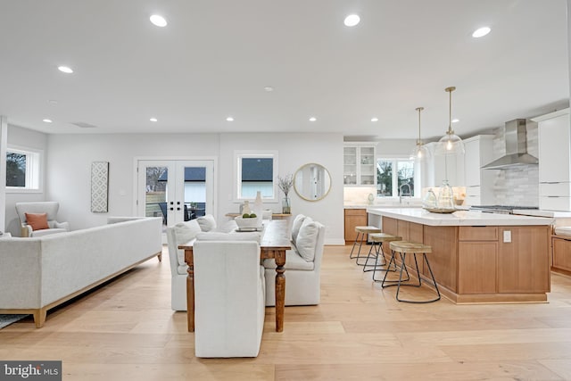 kitchen with light wood-type flooring, wall chimney exhaust hood, open floor plan, and recessed lighting