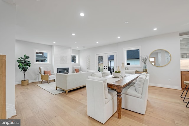 dining space featuring a large fireplace, french doors, light wood-style flooring, and recessed lighting