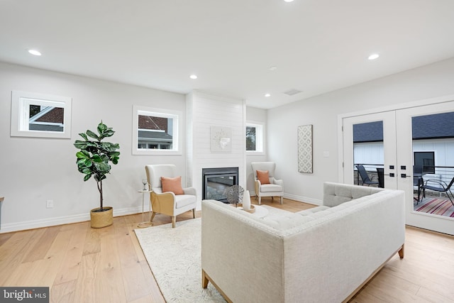 living room featuring recessed lighting, a fireplace, visible vents, light wood-style floors, and french doors