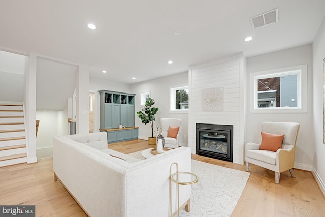 living area featuring visible vents, light wood-style flooring, stairs, a fireplace, and recessed lighting