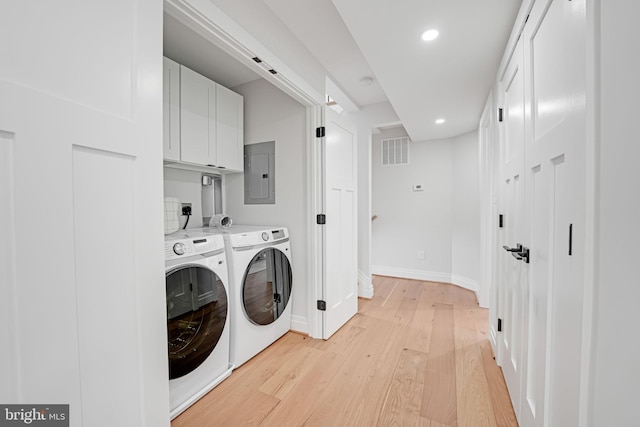 clothes washing area featuring visible vents, light wood-style floors, cabinet space, electric panel, and washer and clothes dryer