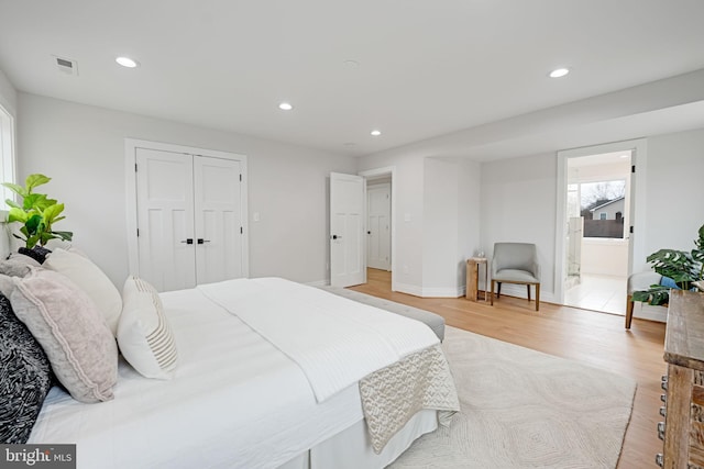 bedroom featuring recessed lighting, visible vents, light wood-style flooring, ensuite bath, and baseboards