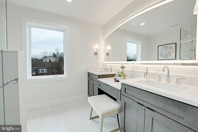 full bath featuring double vanity, baseboards, visible vents, and a sink