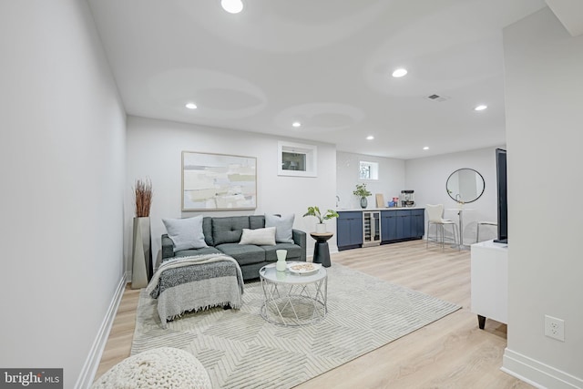 living area with recessed lighting, visible vents, light wood-type flooring, beverage cooler, and baseboards