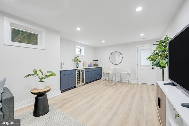 bar featuring recessed lighting, beverage cooler, baseboards, light wood-type flooring, and wet bar