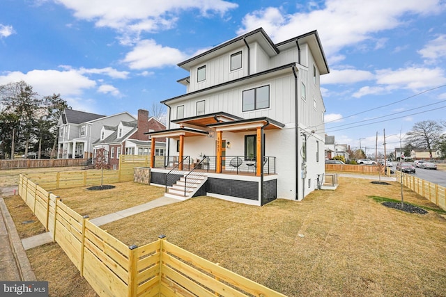 view of front of home with fence private yard, a residential view, a front lawn, and board and batten siding