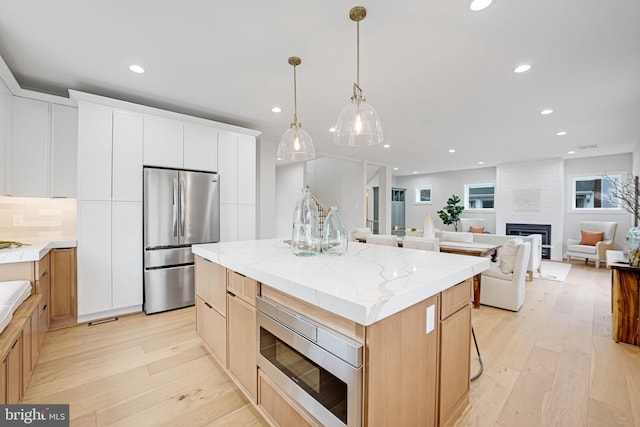 kitchen with appliances with stainless steel finishes, light wood-type flooring, a center island, and recessed lighting