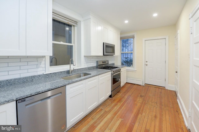 kitchen with backsplash, sink, white cabinetry, and stainless steel appliances