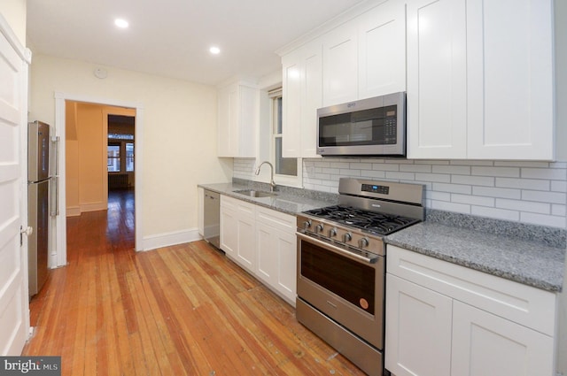 kitchen with light stone counters, sink, white cabinets, and stainless steel appliances