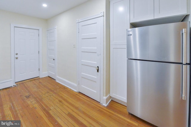 kitchen with white cabinets, stainless steel fridge, and light wood-type flooring