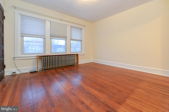 unfurnished room with dark hardwood / wood-style flooring and radiator heating unit