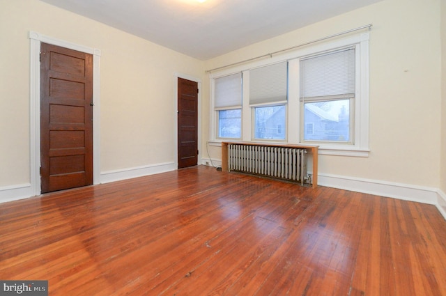 spare room with hardwood / wood-style floors and radiator heating unit