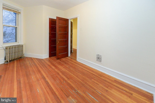 empty room featuring hardwood / wood-style flooring and radiator