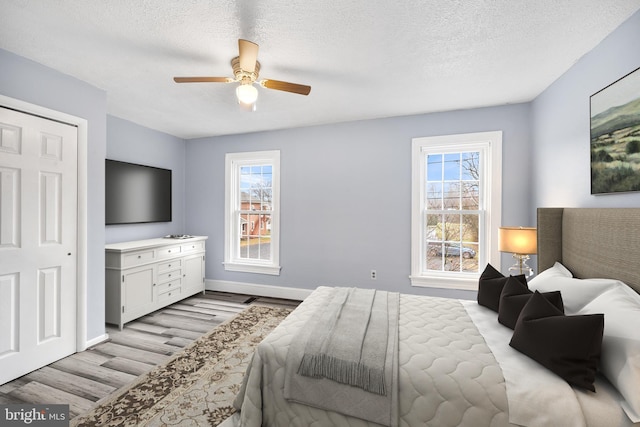 bedroom featuring a textured ceiling, light wood-type flooring, and ceiling fan