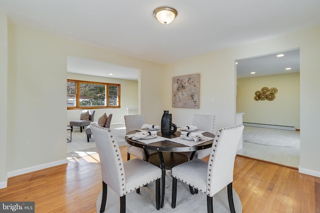 dining area with a baseboard heating unit and light wood-type flooring